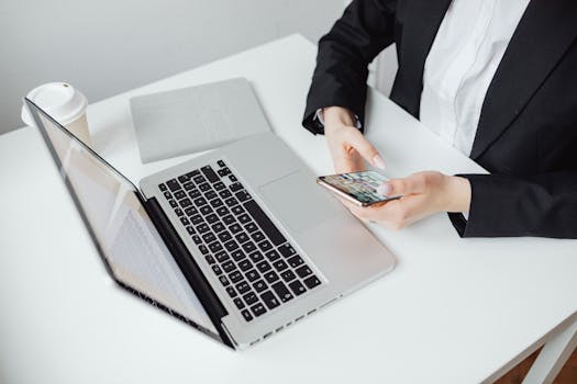 Build AI Receptionist SaaS with Lovable & OpenAI 3 Businesswoman using smartphone at desk with laptop and coffee cup doing business using Ai receptionist.